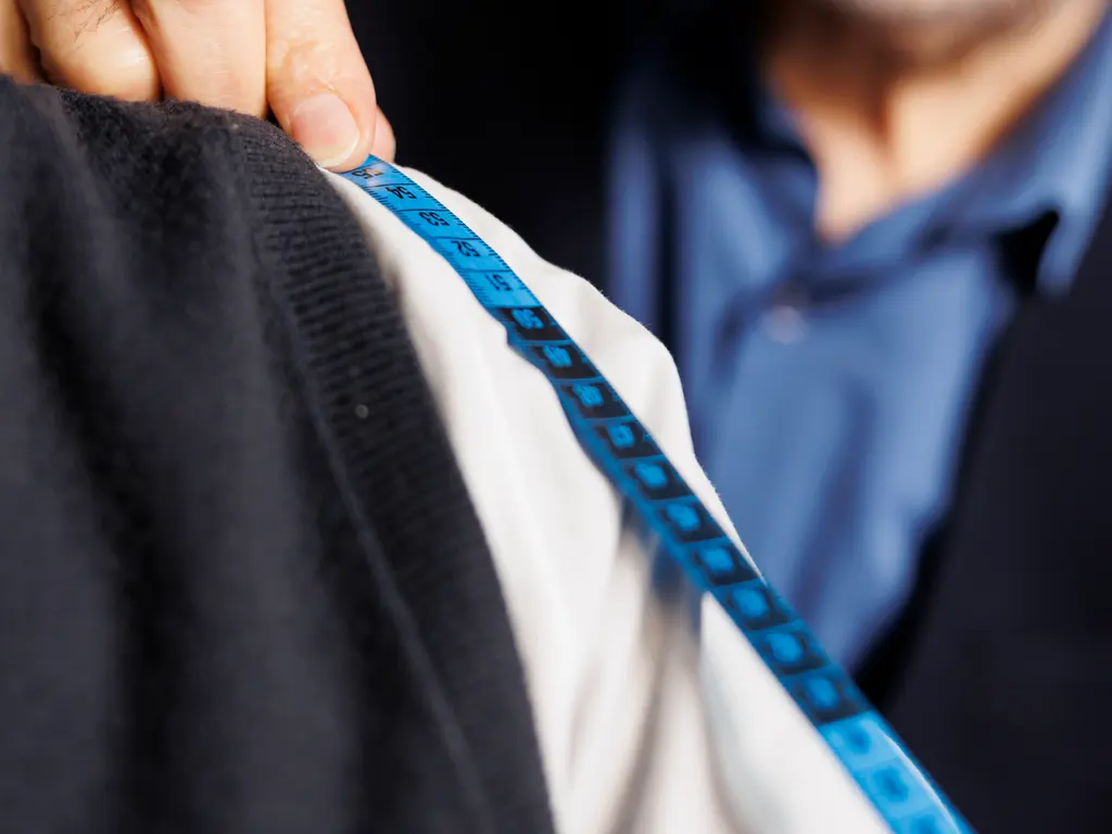 Close-up of a tape measure laid along a folded garment to record its width