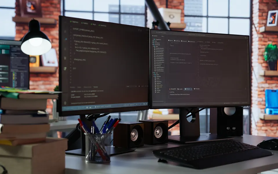 A development desk with code on dual monitors (illustrative photo)