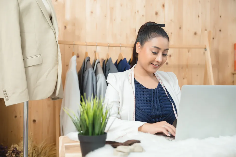 Store owner calmly answering customer questions on a laptop in morning light (illustrative photo)