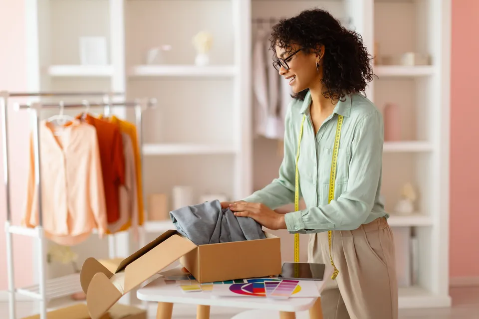 Apparel store owner inspecting a returned garment at the packing table (illustrative photo)